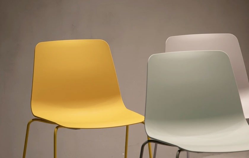 three minimalistic plastic chairs; one yellow, one green and one white