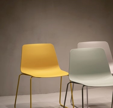 three minimalistic plastic chairs; one yellow, one green and one white